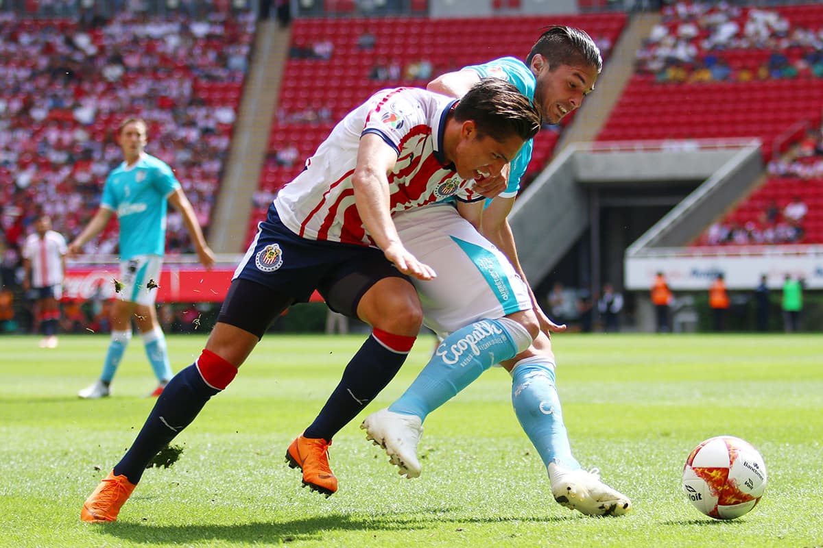 Disputa por el balón entre Alan Cervantes de Chivas (centro) y Javier Guemez de Querétaro.
